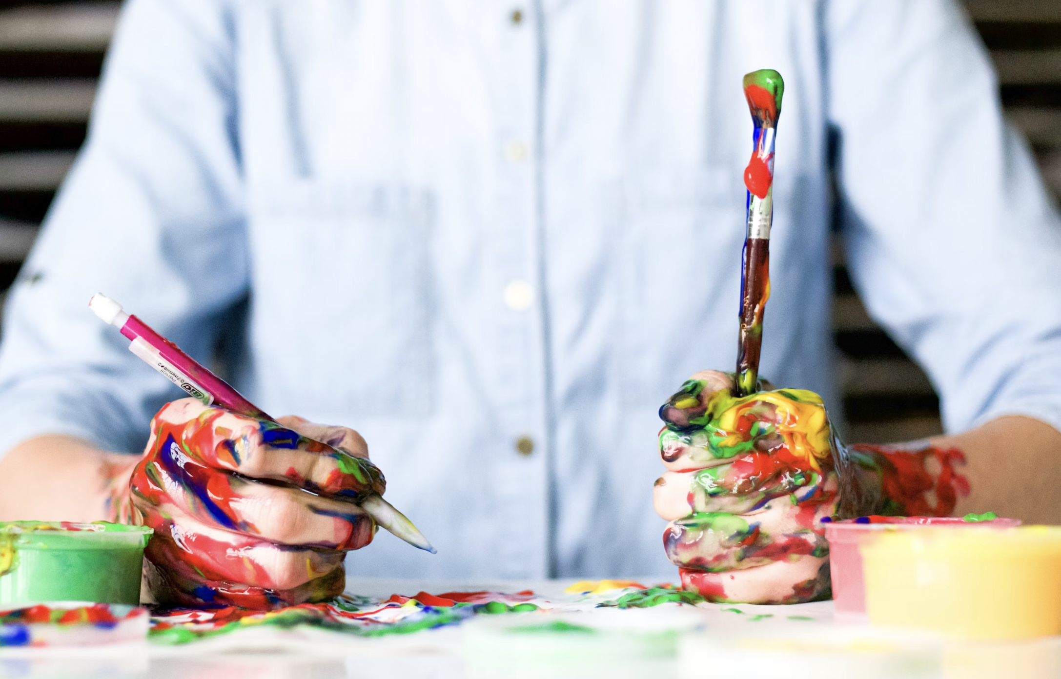 an image of a man holding a paintbrusha nd pencil in his hands and they're covered in paint