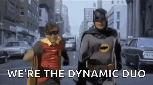 60s style batman and robin running together on the street