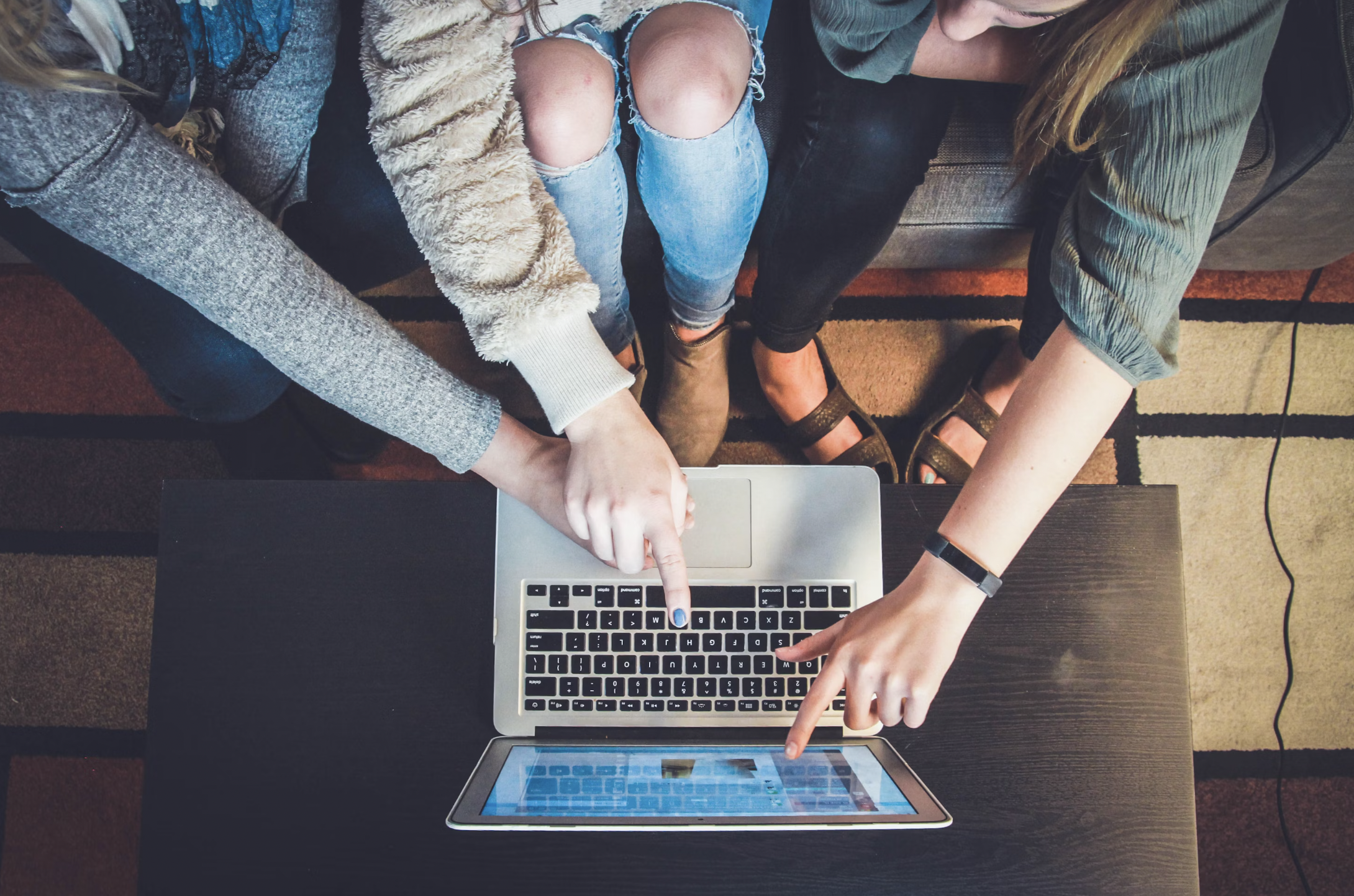 a team of people pointing at the laptop monitor signifying breaking silos 